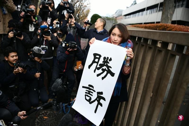 伊藤在法庭外接受媒体访问时举着写上“胜诉”的标语。(法新社) 伊藤在法庭外接受媒体访问时举着写上“胜诉”的标语。(法新社)