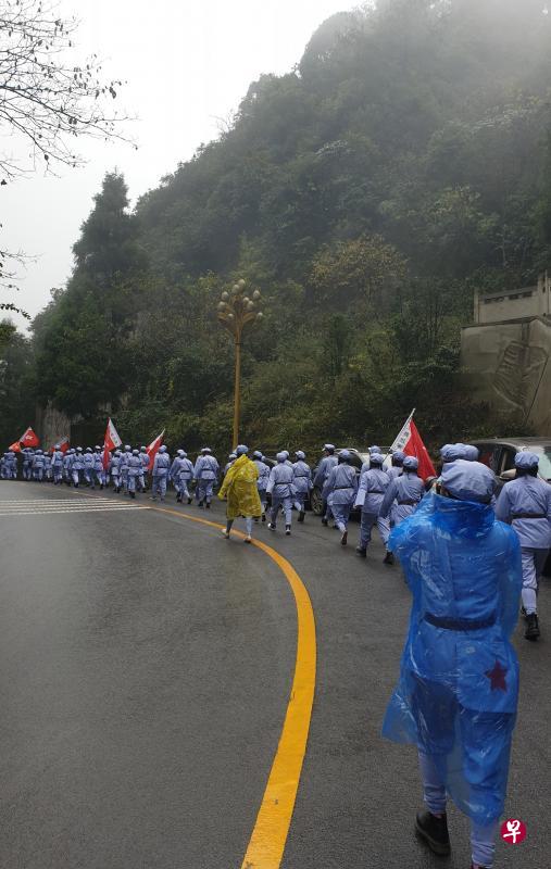 西南大学的研究生身穿红军装,在细雨大雾中迈步向海拔超过1000米的娄山关。(王纬温摄) 西南大学的研究生身穿红军装,在细雨大雾中迈步向海拔超过1000米的娄山关。(王纬温摄)