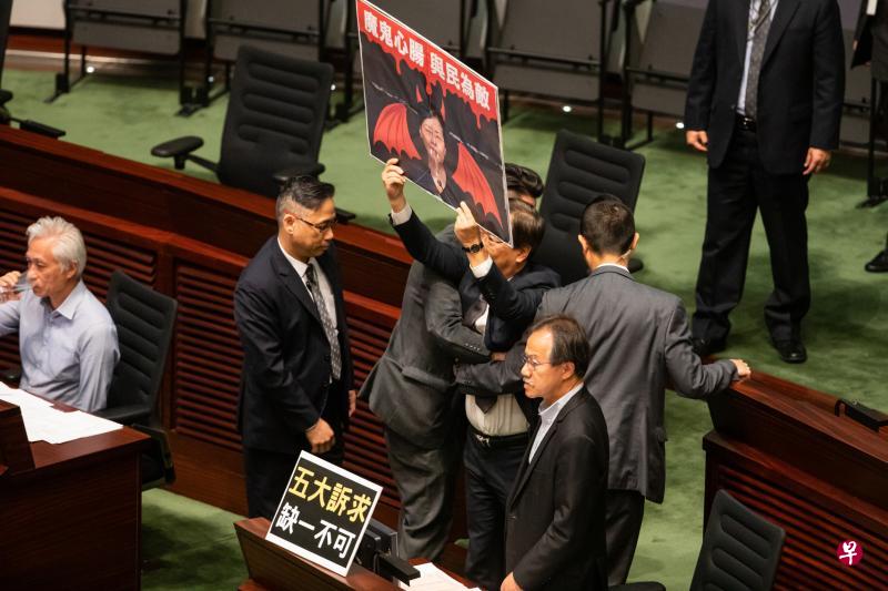昨天的特首答问会扰攘不已,立法会主席梁君彦先后要求13名议员离开会议厅,包括图中举牌的泛民议员郭家麒。(彭博社) 昨天的特首答问会扰攘不已,立法会主席梁君彦先后要求13名议员离开会议厅,包括图中举牌的泛民议员郭家麒。(彭博社)