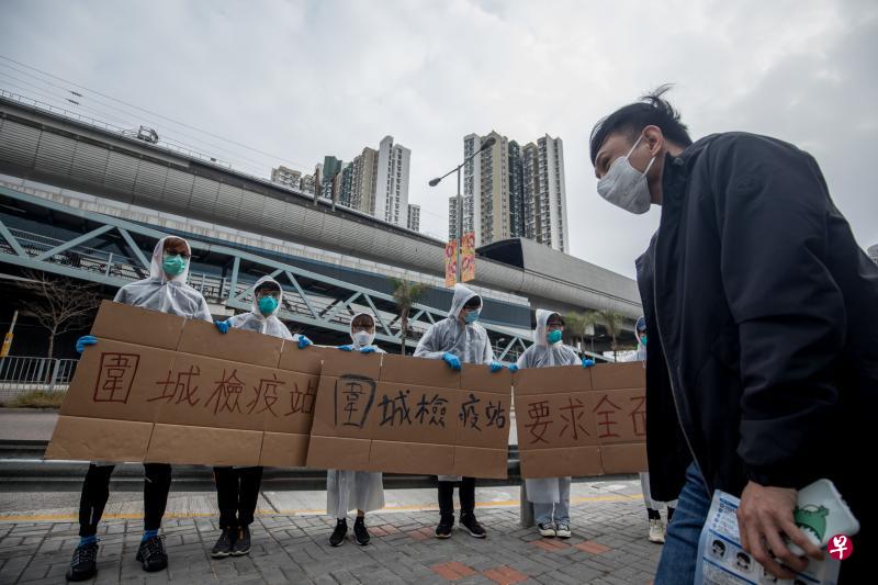 志愿者昨天在深圳湾口岸巴士站附近设置测温点，其中有人举牌要求香港政府全面封闭与中国大陆接壤的边境口岸。（彭博社）