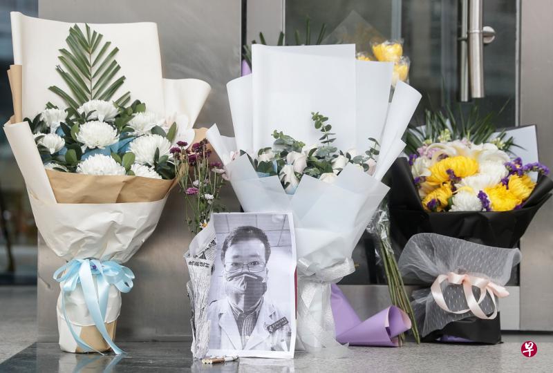 昨天在李文亮生前工作过的武汉中心医院后湖院区门诊楼门口,市民自发前来敬献花束,并以三根香烟代表三炷香,表达哀思。(法新社) 昨天在李文亮生前工作过的武汉中心医院后湖院区门诊楼门口,市民自发前来敬献花束,并以三根香烟代表三炷香,表达哀思。(法新社)