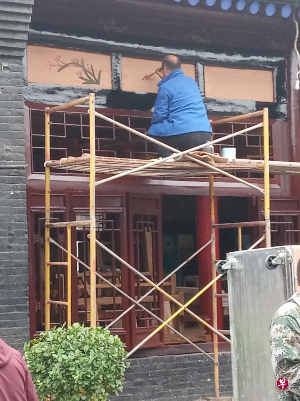 工匠在大门上檐绘图。 工匠在大门上檐绘图。