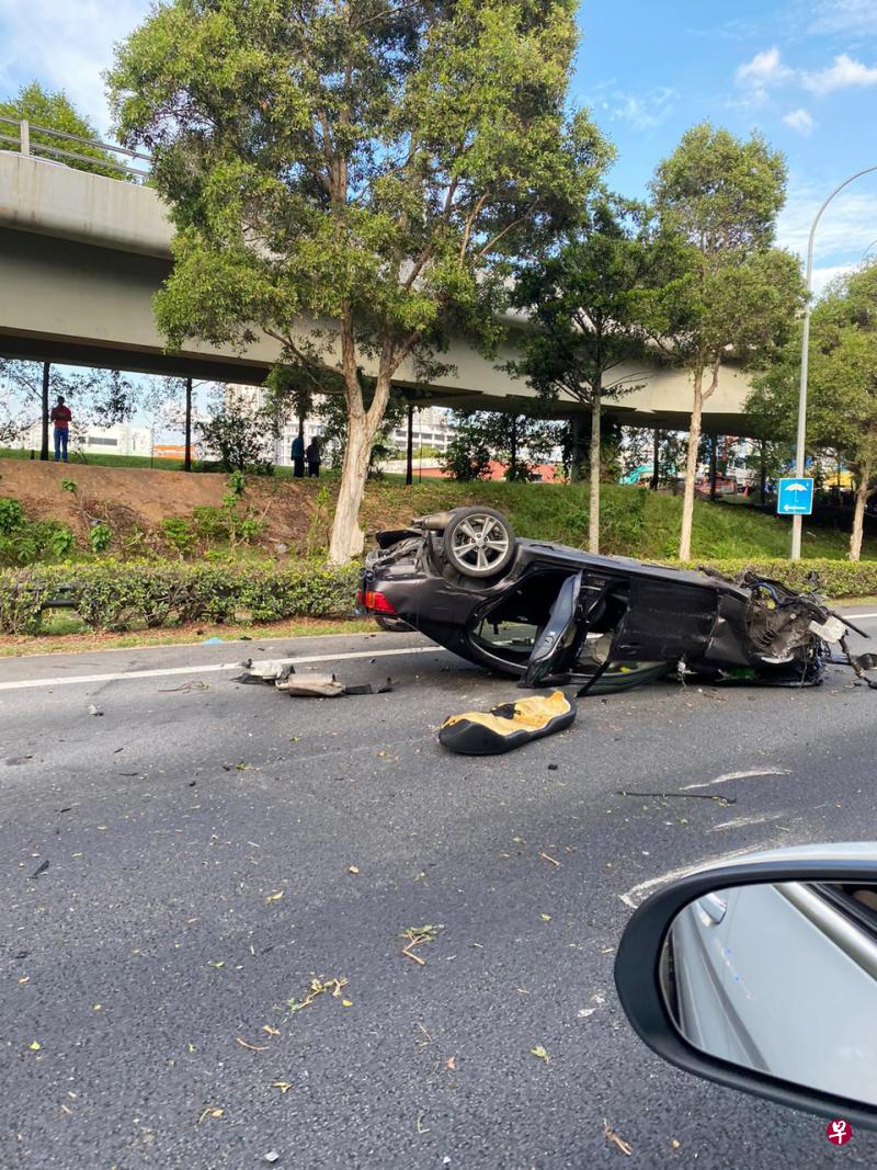 黑色汽车撞上护栏后,整辆车翻覆在快速公路中央,车身严重毁坏,车内三名乘客送院。(读者提供) 黑色汽车撞上护栏后,整辆车翻覆在快速公路中央,车身严重毁坏,车内三名乘客送院。(读者提供)
