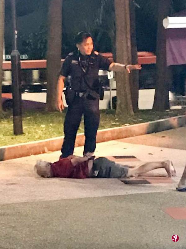 涉案男子在组屋附近被四名男子制伏,警员到场后将他上手铐逮捕。(受访者提供) 涉案男子在组屋附近被四名男子制伏,警员到场后将他上手铐逮捕。(受访者提供)