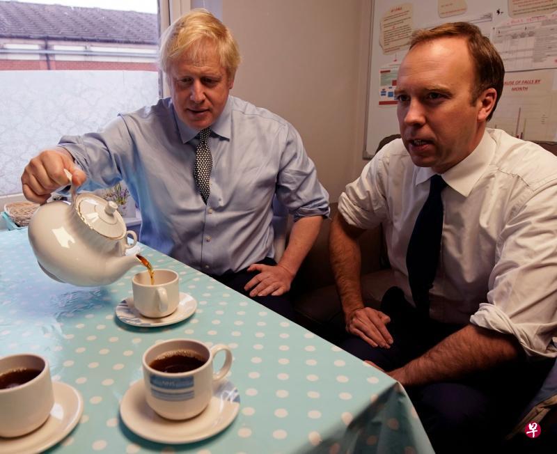 英国首相约翰逊和卫生部长汉考克双双确诊，图为两人去年11月22日在英格兰沃克索普出席保守党的活动时一起喝茶。（法新社）