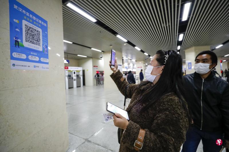 武汉地铁乘客进站必须在安检点出示健康码及检测体温。乘客昨天使用手机应用扫描“武汉市实名登记乘车码”,获得绿码后方可进站。 (新华社) 武汉地铁乘客进站必须在安检点出示健康码及检测体温。乘客昨天使用手机应用扫描“武汉市实名登记乘车码”,获得绿码后方可进站。 (新华社)