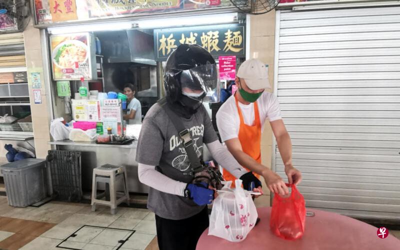 昨早9时,文礼坊小贩中心槟城虾面摊老板卢韦宏(右)接到送餐订单,五分钟内送餐员抵达取货。(温伟中摄) 昨早9时,文礼坊小贩中心槟城虾面摊老板卢韦宏(右)接到送餐订单,五分钟内送餐员抵达取货。(温伟中摄)