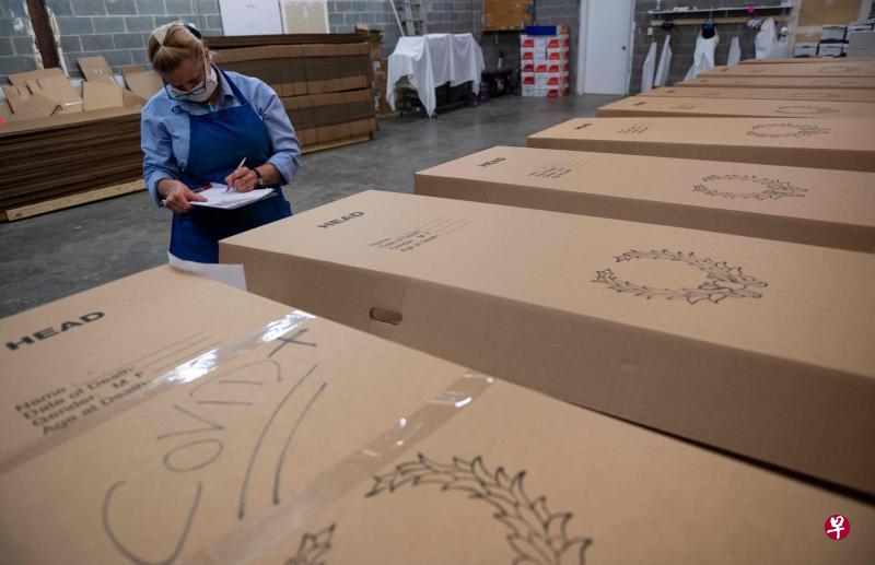 在美国马里兰州米勒斯维尔的殡葬服务中心,员工17日在将纸制棺木送去火化之前,再仔细查看棺木上的死者名字。由于冠病疫情肆虐,这家殡葬服务中心过去三周送去火化的纸制棺木增加30%。(法新社) 在美国马里兰州米勒斯维尔的殡葬服务中心,员工17日在将纸制棺木送去火化之前,再仔细查看棺木上的死者名字。由于冠病疫情肆虐,这家殡葬服务中心过去三周送去火化的纸制棺木增加30%。(法新社)