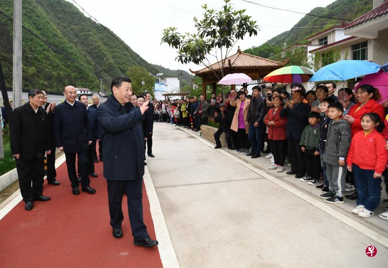 习近平（左三）到位于秦岭深处的柞水县考察村民脱贫情况时向村民致意。（新华社）