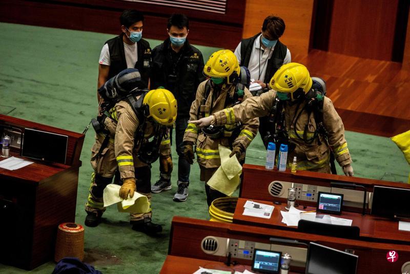 香港立法会昨天审议《国歌法》,本土派议员朱凯廸突然冲向主席台并投掷有臭味液体,导致会议暂停,大批警员与消防员事后进入会议厅进行调查,并取走有关容器。(法新社) 香港立法会昨天审议《国歌法》,本土派议员朱凯廸突然冲向主席台并投掷有臭味液体,导致会议暂停,大批警员与消防员事后进入会议厅进行调查,并取走有关容器。(法新社)