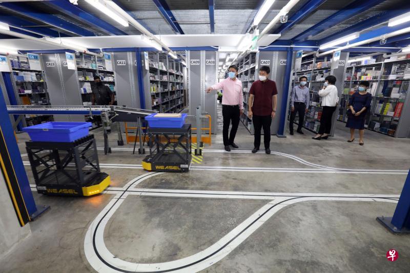 Markono印刷媒体公司董事经理黄耀隆(左)陪同贸工部兼教育部高级政务部长徐芳达走访公司生产线,该公司在进行数码化转型及推动自动化生产,包括运用图中自动引导运输车来提高货品分配效率。(邝启聪摄) Markono印刷媒体公司董事经理黄耀隆(左)陪同贸工部兼教育部高级政务部长徐芳达走访公司生产线,该公司在进行数码化转型及推动自动化生产,包括运用图中自动引导运输车来提高货品分配效率。(邝启聪摄)