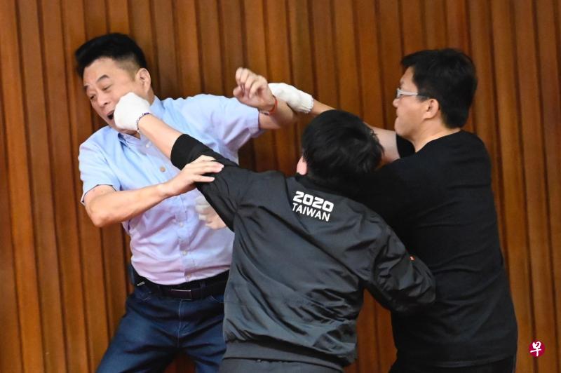 国民党立委鲁明哲(左)与民进党立委吴秉叡(中)、张廖万坚在议场内打成一团。(法新社) 国民党立委鲁明哲(左)与民进党立委吴秉叡(中)、张廖万坚在议场内打成一团。(法新社)