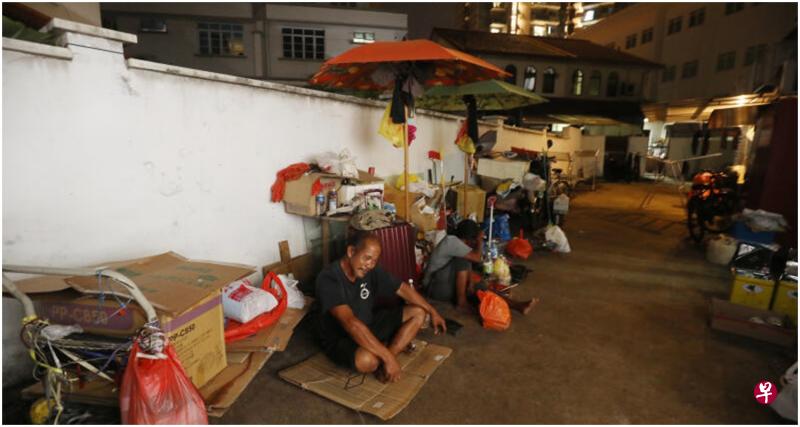 拾荒叔王先生及太太在实龙岗路上段店屋的后巷用纸皮垫着坐下，他们常常就这样坐在后巷露宿。（唐家鸿摄）