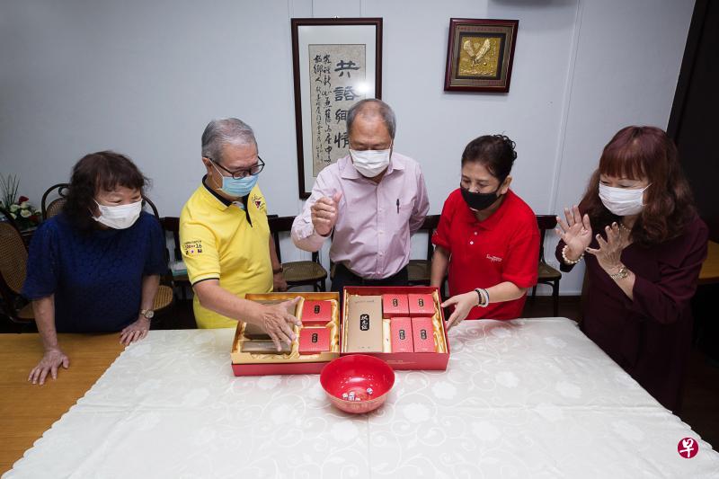 博饼是厦门人庆中秋时的红火游戏。新加坡厦门公会总务黄碧梅（左起）、副会长兼博饼活动筹委会主席陈兴庭、会长汪家裕、会务顾问林璒利和财政叶金英，示范掷骰子“博一把”。（特约蔡家增摄）