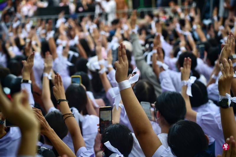 聚集在泰国教育部外的高中生,每人手系白色丝带,竖起三只手指,要求改革在他们看来已经过时的教育制度。(法新社) 聚集在泰国教育部外的高中生,每人手系白色丝带,竖起三只手指,要求改革在他们看来已经过时的教育制度。(法新社)