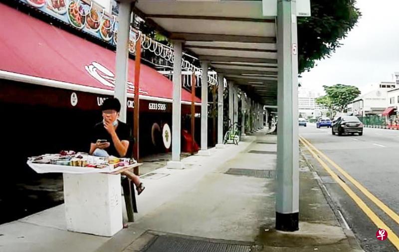 男子坐在有盖走道上,边卖春药边抽烟。(读者提供) 男子坐在有盖走道上,边卖春药边抽烟。(读者提供)