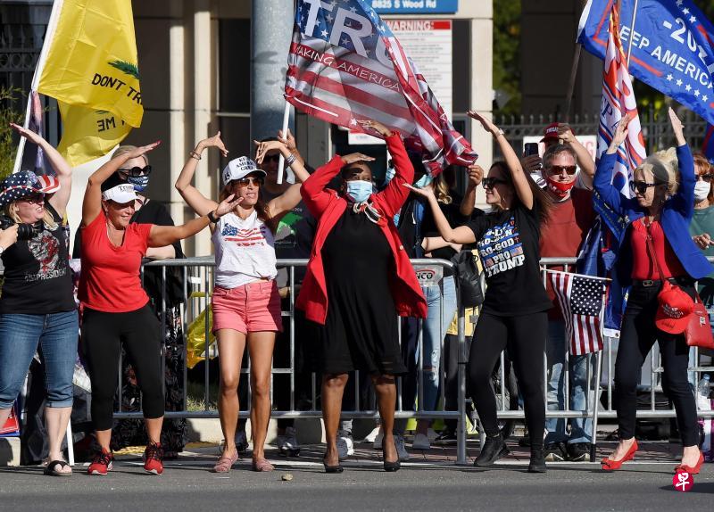 一批不戴口罩的特朗普支持者周一在沃尔特·里德国家军事医疗中心外手舞足蹈,庆祝特朗普出院。(法新社) 一批不戴口罩的特朗普支持者周一在沃尔特·里德国家军事医疗中心外手舞足蹈,庆祝特朗普出院。(法新社)