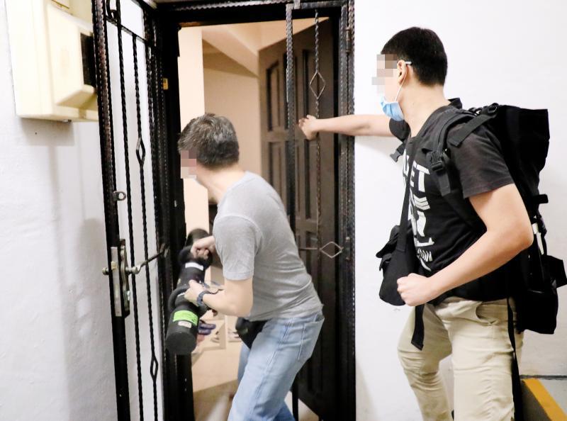 警方在怀疑有非法卖淫活动的组屋外敲门时无人应门,警员于是使用破门器具,撞开木门冲入屋内展开逮捕行动。(林国明摄) 警方在怀疑有非法卖淫活动的组屋外敲门时无人应门,警员于是使用破门器具,撞开木门冲入屋内展开逮捕行动。(林国明摄)