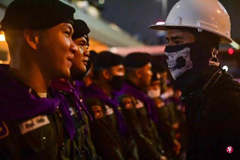 泰国周三继续出现反政府示威。图为一名戴着头盔与口罩的示威者遇上军警组成的人墙。(法新社) 泰国周三继续出现反政府示威。图为一名戴着头盔与口罩的示威者遇上军警组成的人墙。(法新社)