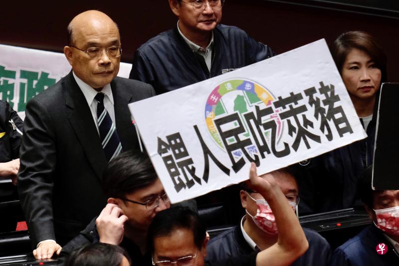 国民党立委今天在台湾立法院举起标语,抗议民进党政府允许进口含莱客多巴胺瘦肉精的美国猪肉(莱猪),并尝试阻止行政院长苏贞昌(左)发表施政报告。(法新社) 国民党立委今天在台湾立法院举起标语,抗议民进党政府允许进口含莱客多巴胺瘦肉精的美国猪肉(莱猪),并尝试阻止行政院长苏贞昌(左)发表施政报告。(法新社)