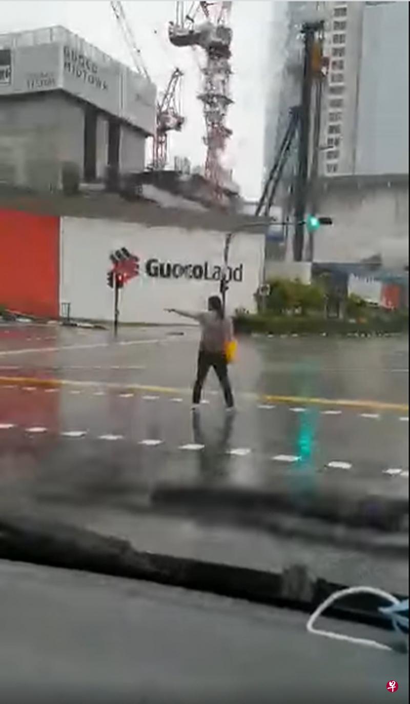 女子不知何故冒雨站在繁忙的交界处挡着车辆前行。(取自面簿) 女子不知何故冒雨站在繁忙的交界处挡着车辆前行。(取自面簿)
