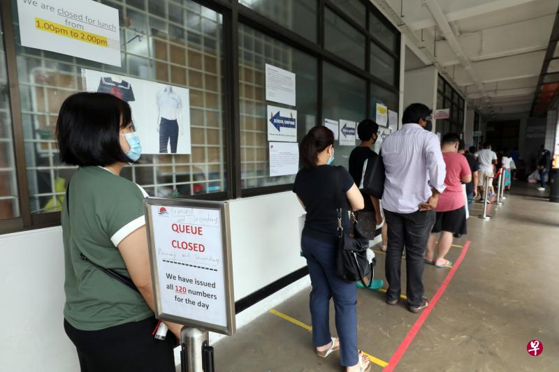 记者昨早走访位于宏茂桥的日新服装店，发现店家已采用派发排队号码，并明确指示营业时间，减少门前排队的人龙。截至中午，所有120个号码已被领取一空。（邝启聪摄）