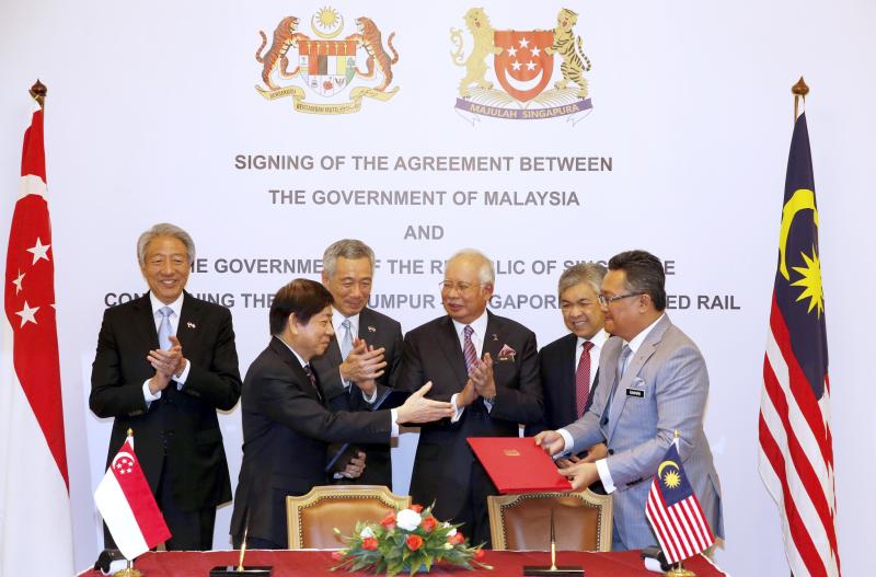我国时任基础建设统筹部长兼交通部长许文远(前排左)和时任马来西亚首相署部长阿都拉曼达兰(前排右),在李显龙总理(后排左二)和时任副总理的国务资政兼国家安全统筹部长张志贤(后排左一),以及时任马来西亚首相纳吉(后排右二)和时任副首相阿末扎希(后排右一)的见证下,于2016年签署新隆高铁双边协定。(档案照片) 我国时任基础建设统筹部长兼交通部长许文远(前排左)和时任马来西亚首相署部长阿都拉曼达兰(前排右),在李显龙总理(后排左二)和时任副总理的国务资政兼国家安全统筹部长张志贤(后排左一),以及时任马来西亚首相纳吉(后排右二)和时任副首相阿末扎希(后排右一)的见证下,于2016年签署新隆高铁双边协定。(档案照片)