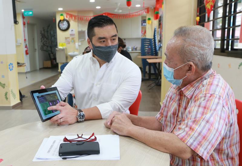 70岁的李景伟(右) 在国大医学院数字医疗研究所转化研究项目主任何鼎教授(左) 的指导下,试玩研究所推出的游戏,活动大脑。(唐家鸿摄) 70岁的李景伟(右) 在国大医学院数字医疗研究所转化研究项目主任何鼎教授(左) 的指导下,试玩研究所推出的游戏,活动大脑。(唐家鸿摄)