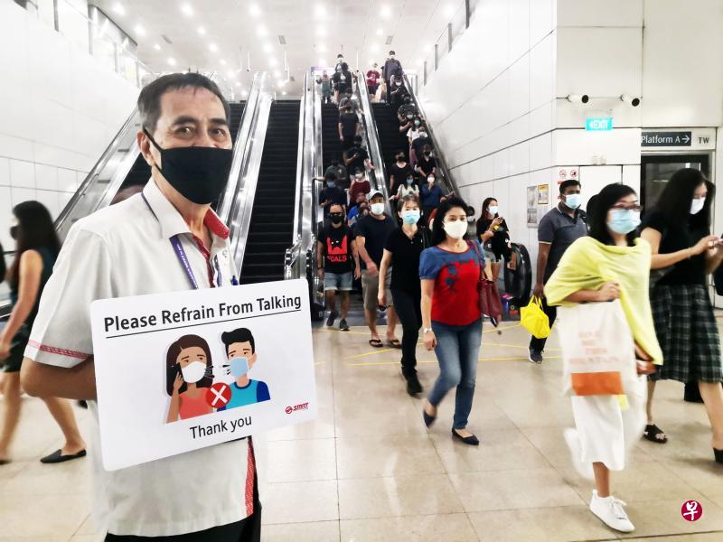 SMRT职员将于高峰时段在地铁站举着提示牌,提醒乘客避免交谈。(庄耿闻摄) SMRT职员将于高峰时段在地铁站举着提示牌,提醒乘客避免交谈。(庄耿闻摄)