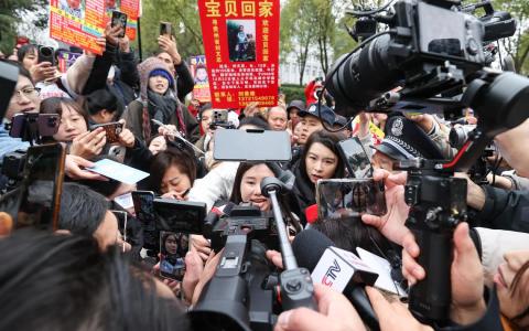 中国贵州人贩子余华英拐卖儿童案件宣判后，受害者杨妞花（中）被围堵采访。杨妞花说，余华英在庭审中表现得非常嚣张，始终不认为自己有错。（中新社）