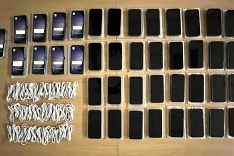 新加坡警察部队起获不同的冒牌手机和配件作为证物，并扣下涉案男子的个人手机进行调查。（新加坡警察部队提供）