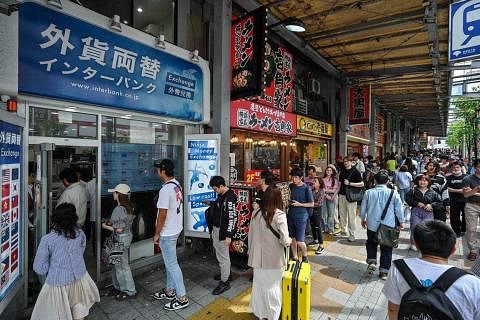 日元币值持续下滑，东京街头的钱币兑换商和食肆游客涌现。（法新社）